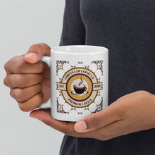 Load image into Gallery viewer, A person holding a white ceramic coffee mug with a circular 'Chiefy's Cup Coffee Co. Premium Coffee' graphic in brown and gold tones, against a neutral gray background.
