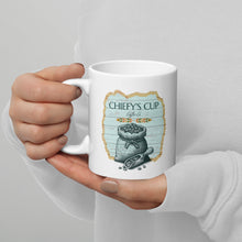 Load image into Gallery viewer, A person in a white ribbed sweater holds a white ceramic mug featuring a vintage-style illustration of a sack of coins with the text 'CHIEFY'S CUP Coffee Co.' on a light gray background.

