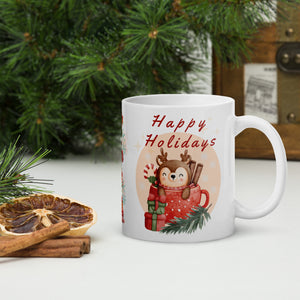 Right side view of a white glossy mug with the phrase "Happy Holidays" in festive font, featuring a baby reindeer inside a mug, red Christmas present, pine tree trimmings, snowflakes, and golden sparkles.