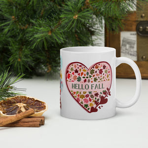 Right side view of a white glossy mug with the phrase "Hello Fall," featuring a heart-shaped leaf design, a red heart-shaped frame, and a pink-hued heart-shaped background.