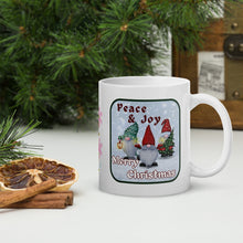 Load image into Gallery viewer, Right side view of a white glossy mug with the phrase &quot;Peace and Joy Merry Christmas&quot; in festive font, featuring a Christmas gnome design with a snowy blue background.
