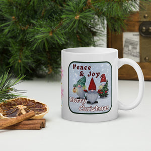 Right side view of a white glossy mug with the phrase "Peace and Joy Merry Christmas" in festive font, featuring a Christmas gnome design with a snowy blue background.