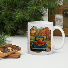 Load image into Gallery viewer, Right side view of a white glossy mug featuring the festive phrase &quot;Fall Harvest&quot; with a design of an old blue truck on a country dirt road, its bed filled with pumpkins and fall leaves, set against a backdrop of autumn-colored trees.
