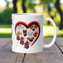 Load image into Gallery viewer, Right side view of a white glossy mug with a bright heart-shaped frame , surrounded by golden sparkles, with one pink, one blue, and one purple paw print on the side of the frame and cute dog faces inside the heart frame.
