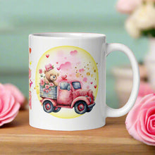 Load image into Gallery viewer, Right-side view of a white glossy mug featuring a cute bear in an old red truck with pink roses in the truck bed, surrounded by pink and red hearts, golden glitter, and a yellow circle.
