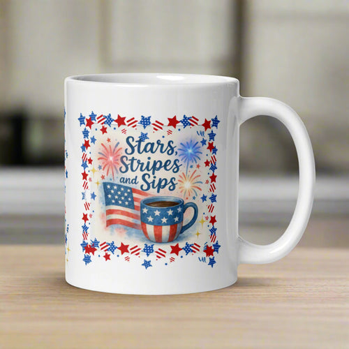 Right side view of white glossy mug featuring an American flag waving beside a cup of coffee decorated with a small American flag. Firecrackers are going off in the background, all framed with a red, white, and blue border.