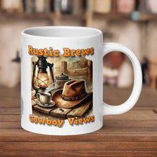 Load image into Gallery viewer, Right side view 20 oz white glossy mug with image phrase &quot;Rustic Brews Cowboy Views,&quot; featuring a rustic cowboy hat resting on a weathered table, with a steaming cup of coffee and an old lantern beside it.
